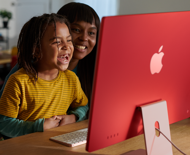 iMac’te hep birlikte bir program seyrederek gülen aile üyeleri.