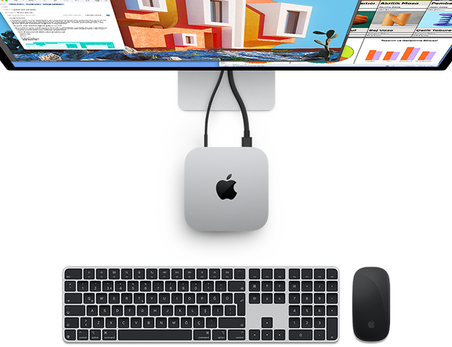 Yanında kablosuz Magic Keyboard ve Magic Mouse bulunan ve bir ekrana bağlı olan gümüş rengi Mac mini’nin, Apple logosuyla birlikte yukarıdan görünümü